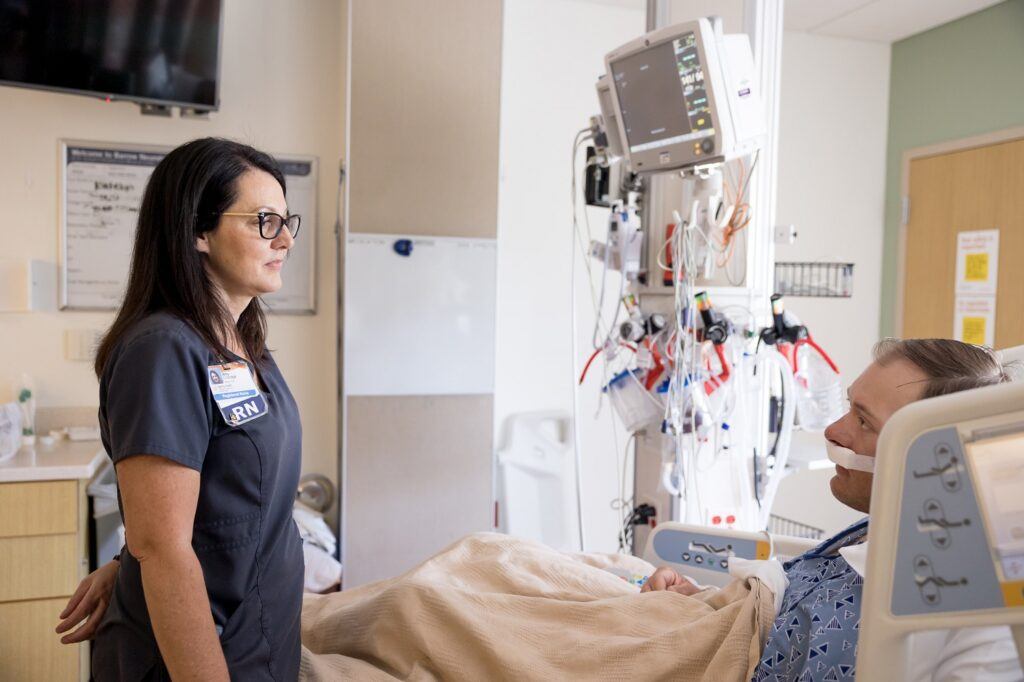 neuroscience nurse talking to a patient in the neurocritical care unit