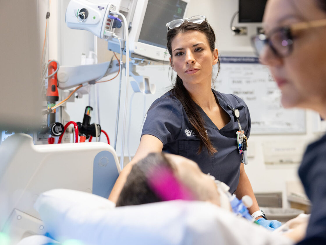 a barrow neuroscience nurse delivering bedside care to a patient in the neurocritical care unit