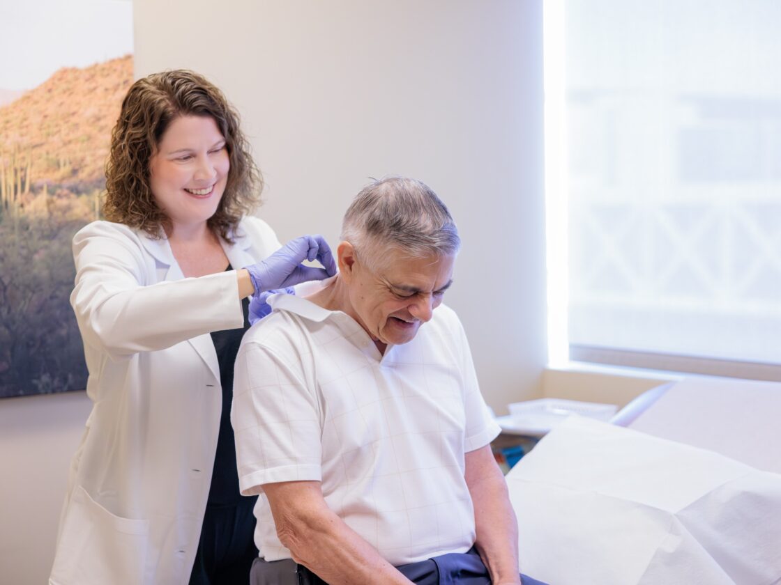Dr. Lindsay Frerichs treating a migraine patient by administering botox injections in an exam room.