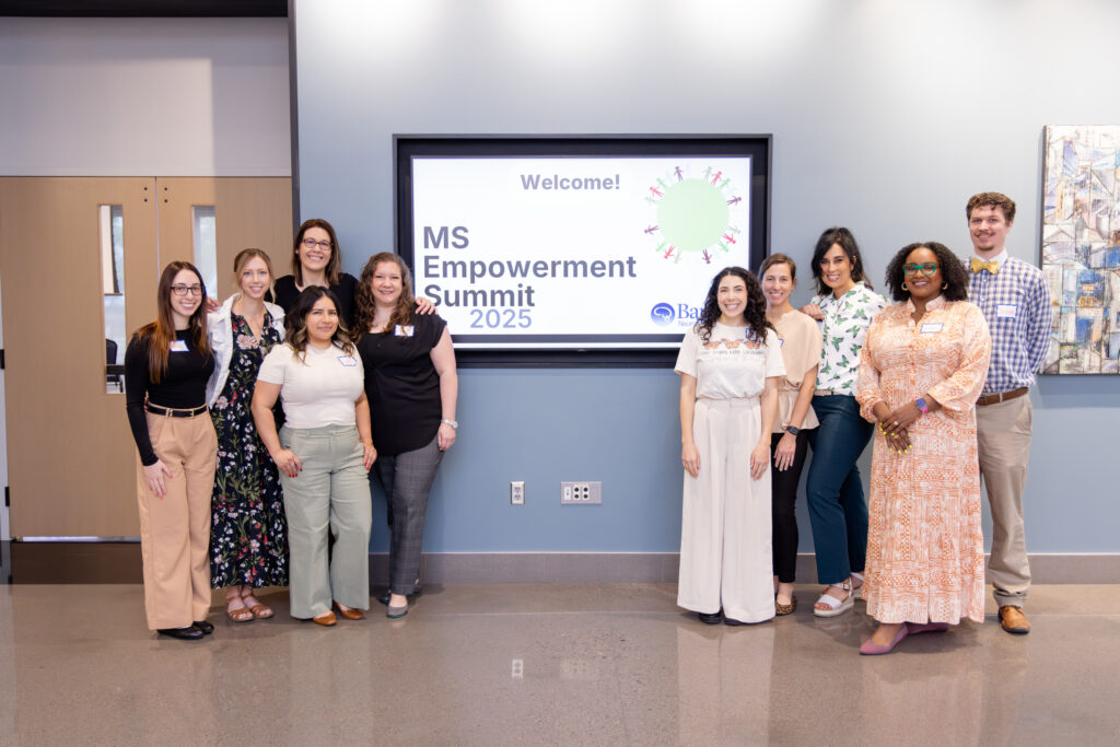 A group stands in front of a monitor that says, "Welcome - MS Empowerment Summit 2025"