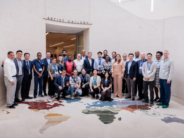 At the Musical Instrument Museum in Phoenix, Arizona, a large group poses for a photo in a room where the floor is a map of the world.