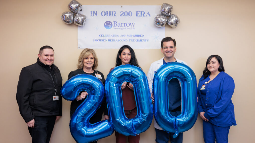 Dr. Ponce and his team hold balloons that spell out 200 while standing in front of a sign that says, "In Our 200 Era: Celebrating 200 MR-Guided Focused Ultrasound Treatments"