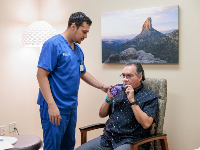 Clinical trial participant undergoes test of breathing function with assistance from Barrow team member