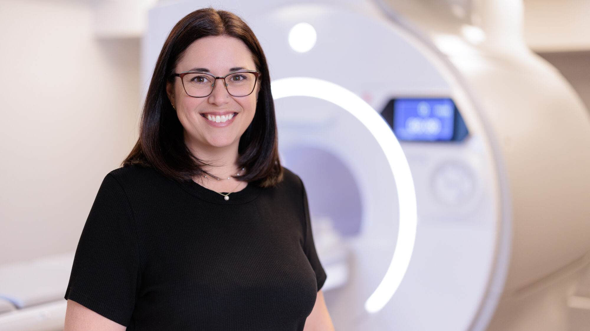 ashley stokes standing in front of GE research MRI machine.