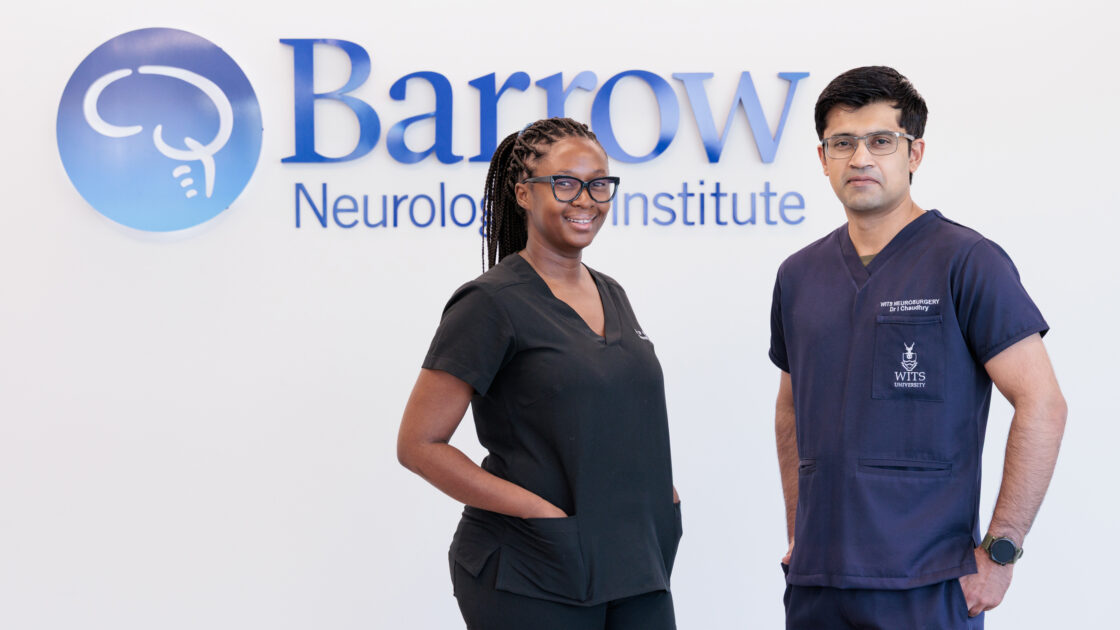 Franke neurology observers Dr. Sandane Chauke-Korae and Dr. Irtiza Chaudhry in front of a Barrow logo in a hospital lobby. They are both wearing scrubs.