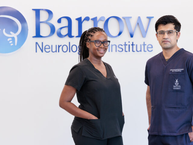 Franke neurology observers Dr. Sandane Chauke-Korae and Dr. Irtiza Chaudhry in front of a Barrow logo in a hospital lobby. They are both wearing scrubs.