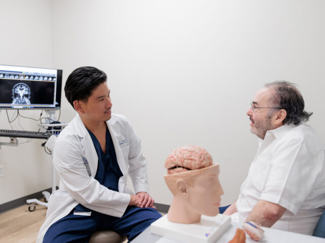 Dr. Yang speaks to patient George Zapien in his clinic at Barrow
