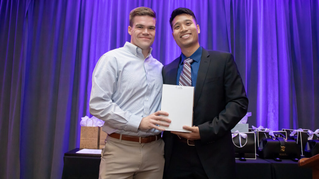 Dr. Timothy Fullam onstage accepting his award from a graduating neurology resident
