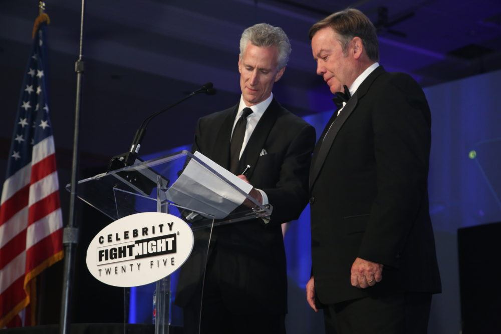 Dr. Michael Lawton and Dr. Michael Crow signing a document on stage at Celebrity Fight Night