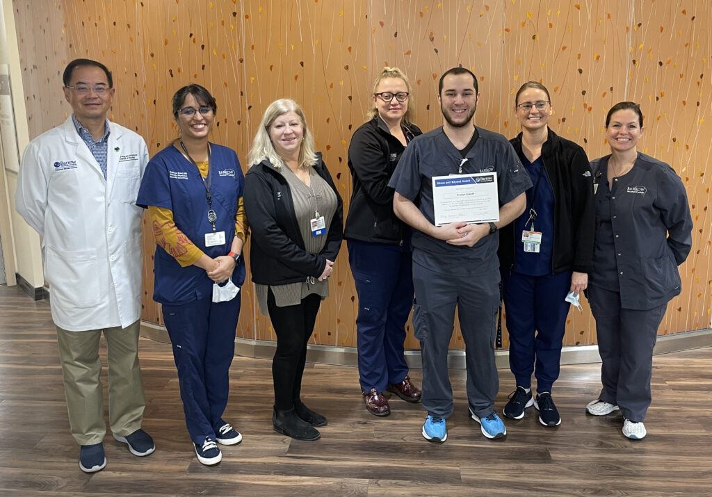 Tristan poses in the hospital with his certificate, surrounded by members of the stroke team