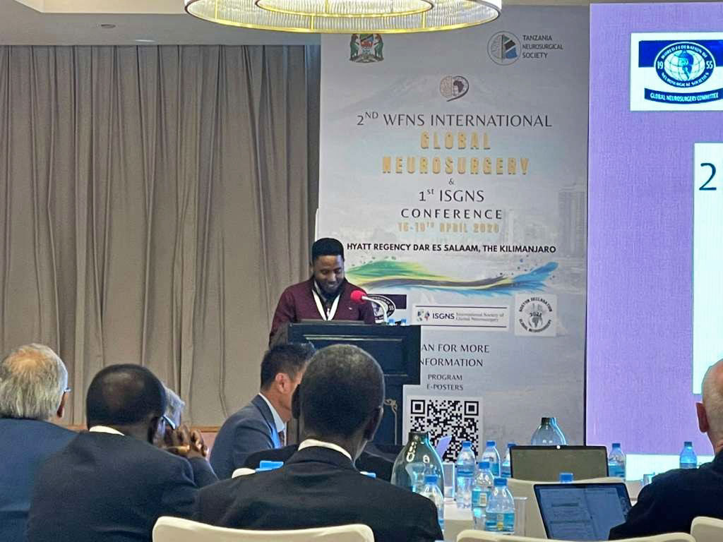 Dr. Goodluck Ndibalema presents on stage at the WFNS/ISGNS Conference