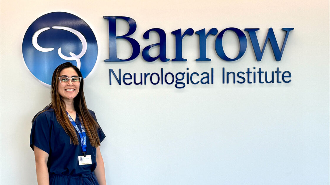 Ashly Arias Obando stands in front of the Barrow logo