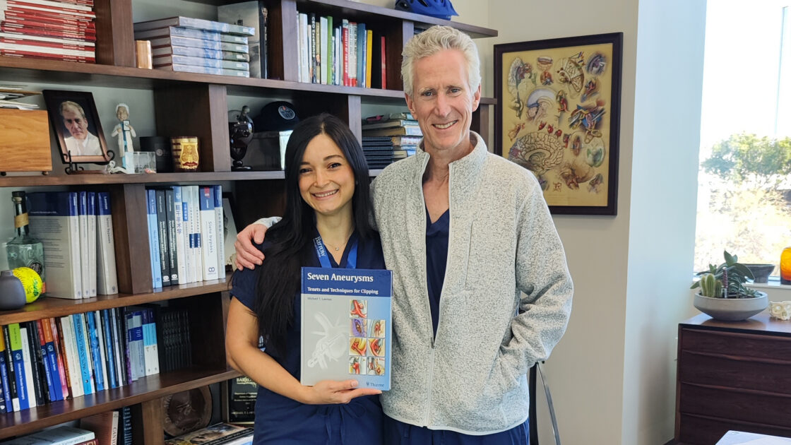 Dr. Ramos Urbina with Dr. Lawton in his office. She is holding a copy of "Seven Aneurysms," a textbook he authored.