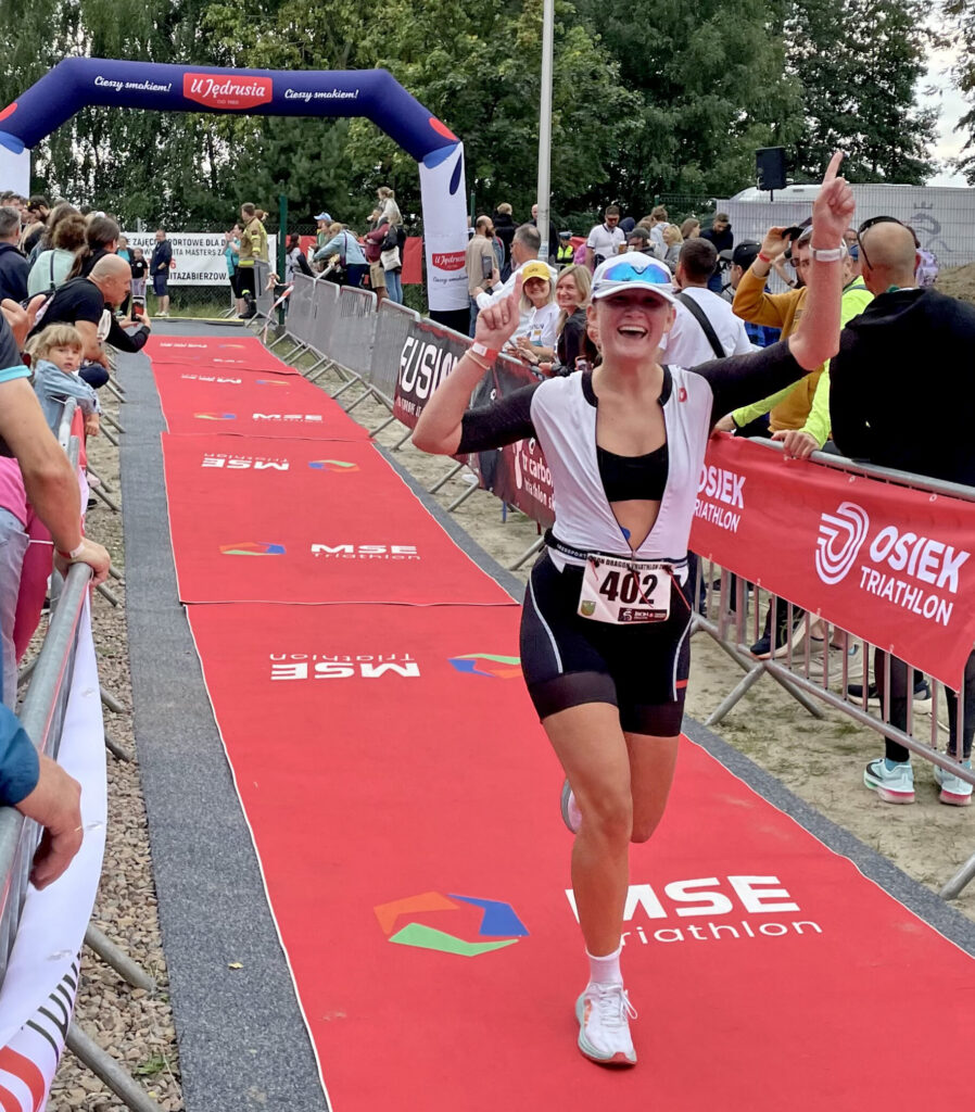 Alexandra celebrates crossing the finish line of a triathlon