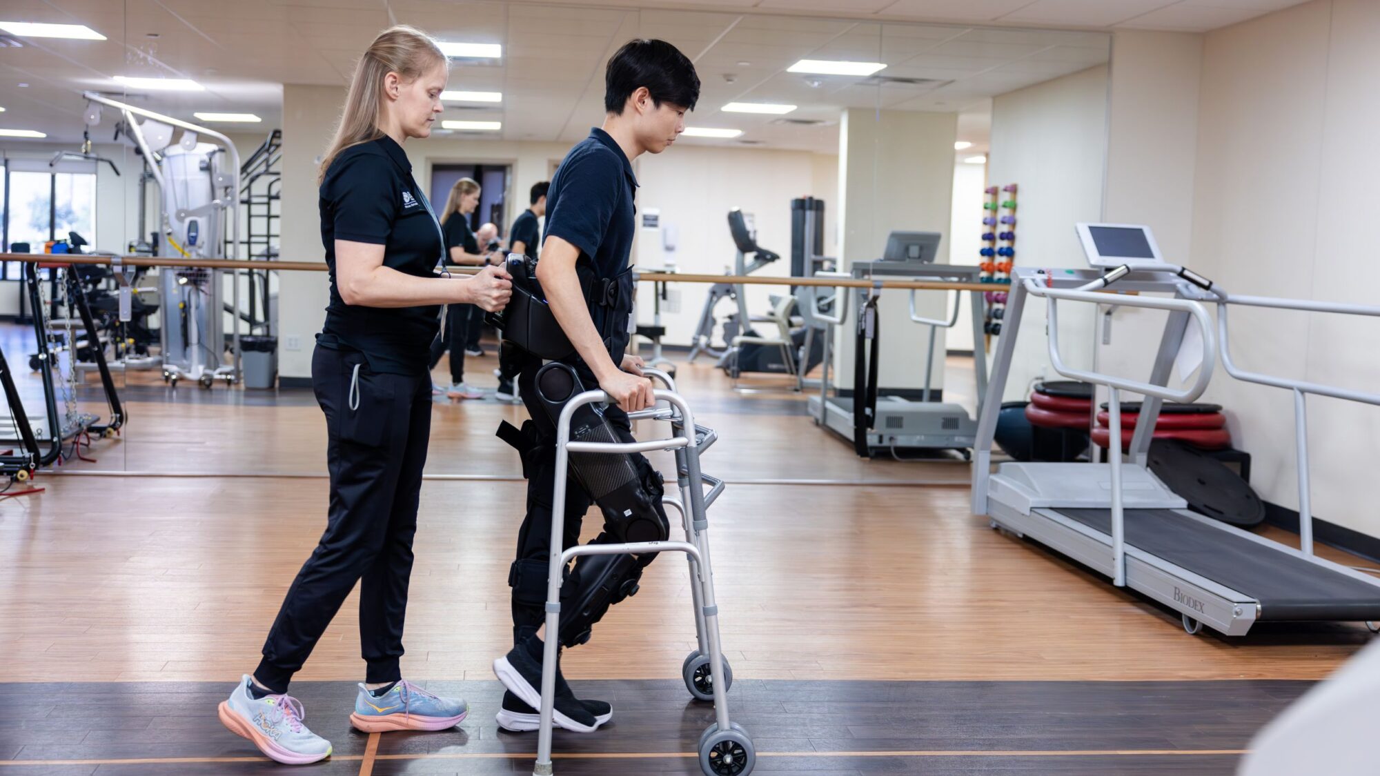 A neuro-rehabilitation specialist helps a patient use the ekso indego device.