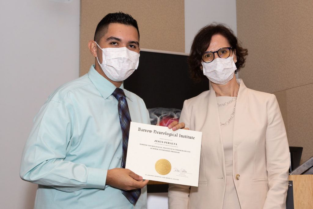 Jesus Peralta is holding a completion certificate and standing next to Dr. Rita Sattler