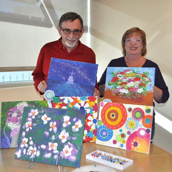 John and Karen O'Donnell pose with their paintings