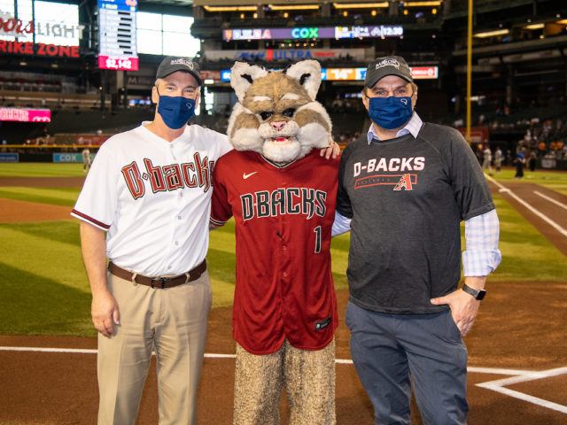 Dr. Robert Bowser and Dr. Fredric Manfredsson pose with Baxter the Bobcat, the Arizona Diamondbacks mascot, on the field