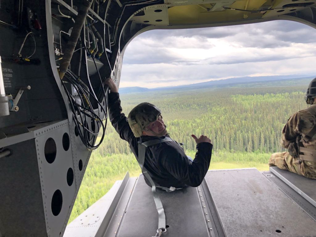 Luke O'Neill is pictured in the back of an Army aircraft. He is looking back at the camera and giving a thumb's up.