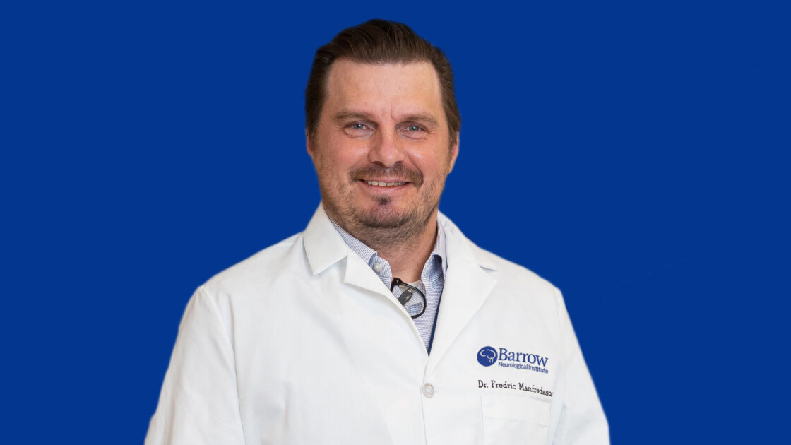 Photo of Dr. Manfredsson in a white lab coat on a blue background