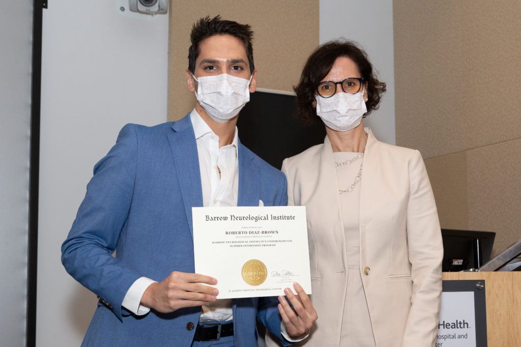 Robert Diaz-Brown holding a completion certificate and standing next to Dr. Rita Sattler.