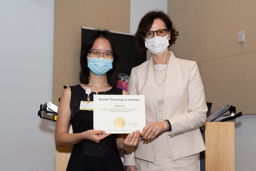 Yijie Guo holding a completion certificate and standing next to Dr. Rita Sattler