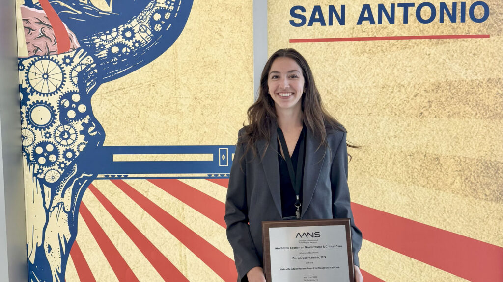 Sarah Sterbanch poses with her plaque in front of a AANS San Antonio signage
