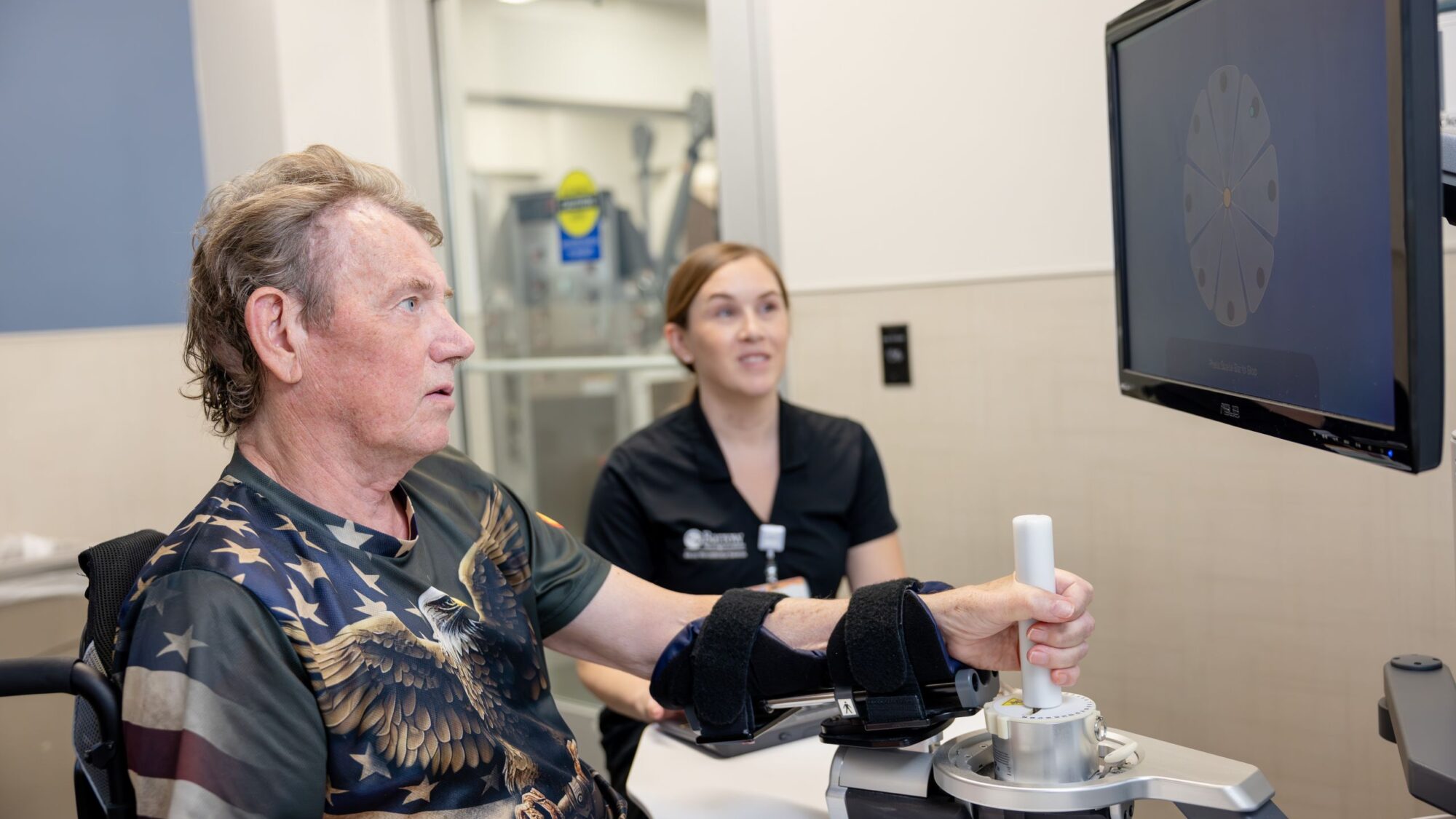 A patient uses the BIONIK Inmotion arm and hand with assistance from a neuro-rehabilitation specialist.