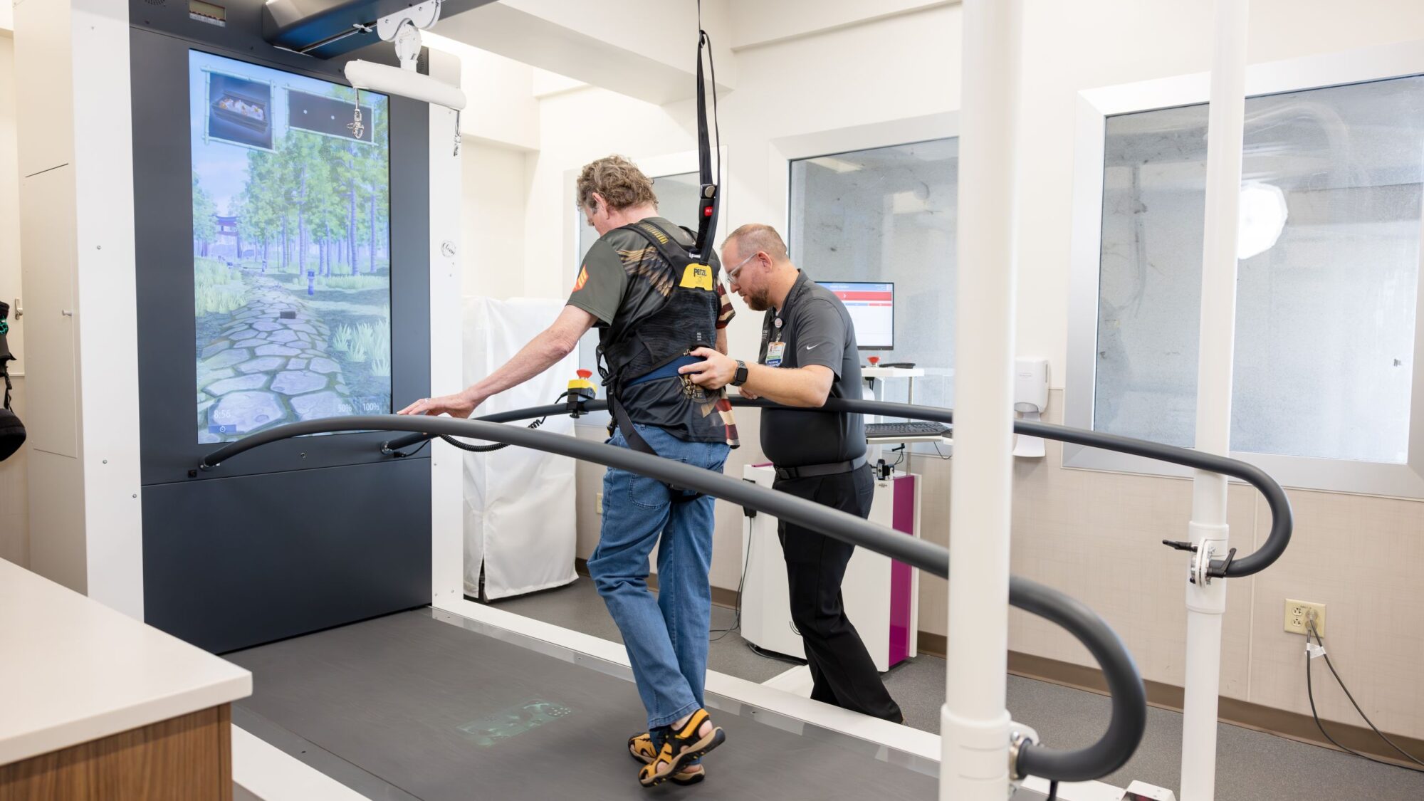 A patient uses the C-Mill by Motek treadmill with the assistance of a physical therapist.