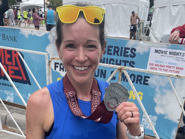 Christi Endicott smiles and holds up her race medal near the finish line of the Santa Rosa Marathon