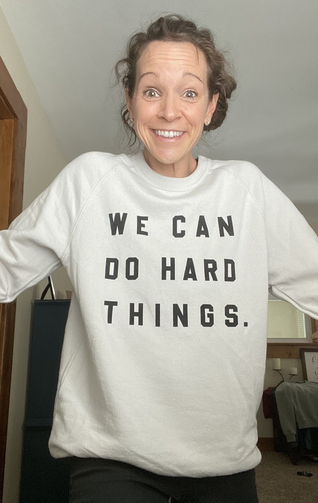 Christi smiles while wearing a sweatshirt that reads: "We can do hard things"