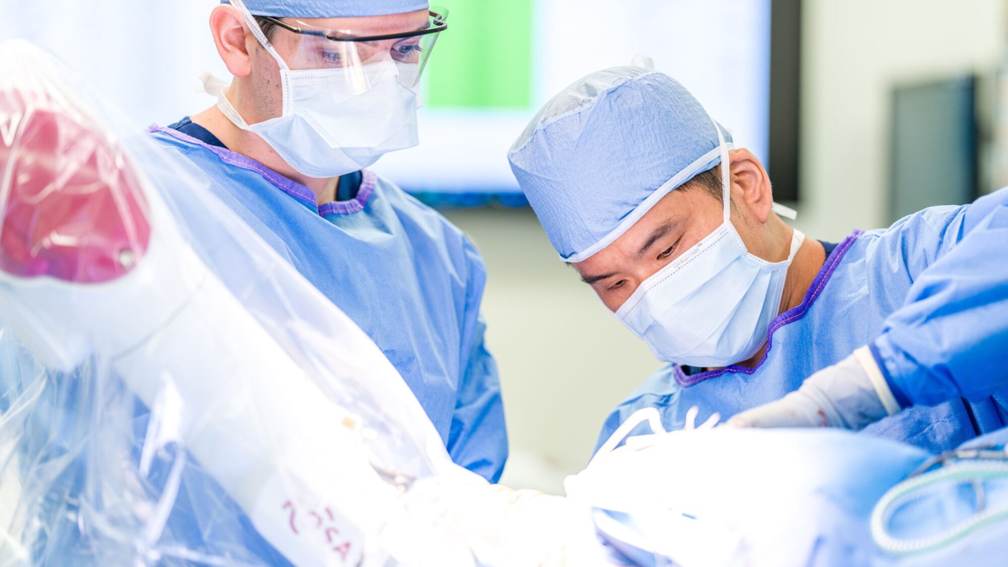 Neurosurgeon Dr. Andrew Yang and neurosurgery resident performing surgery in operating room.