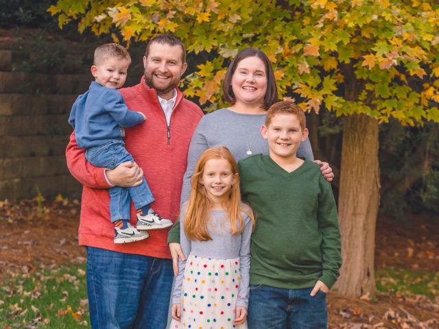 Photo of Hope Terry, her husband, and their three kids in front of fall foliage