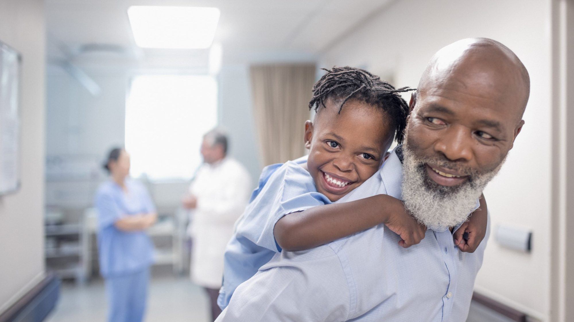 father giving son a piggyback in hospital