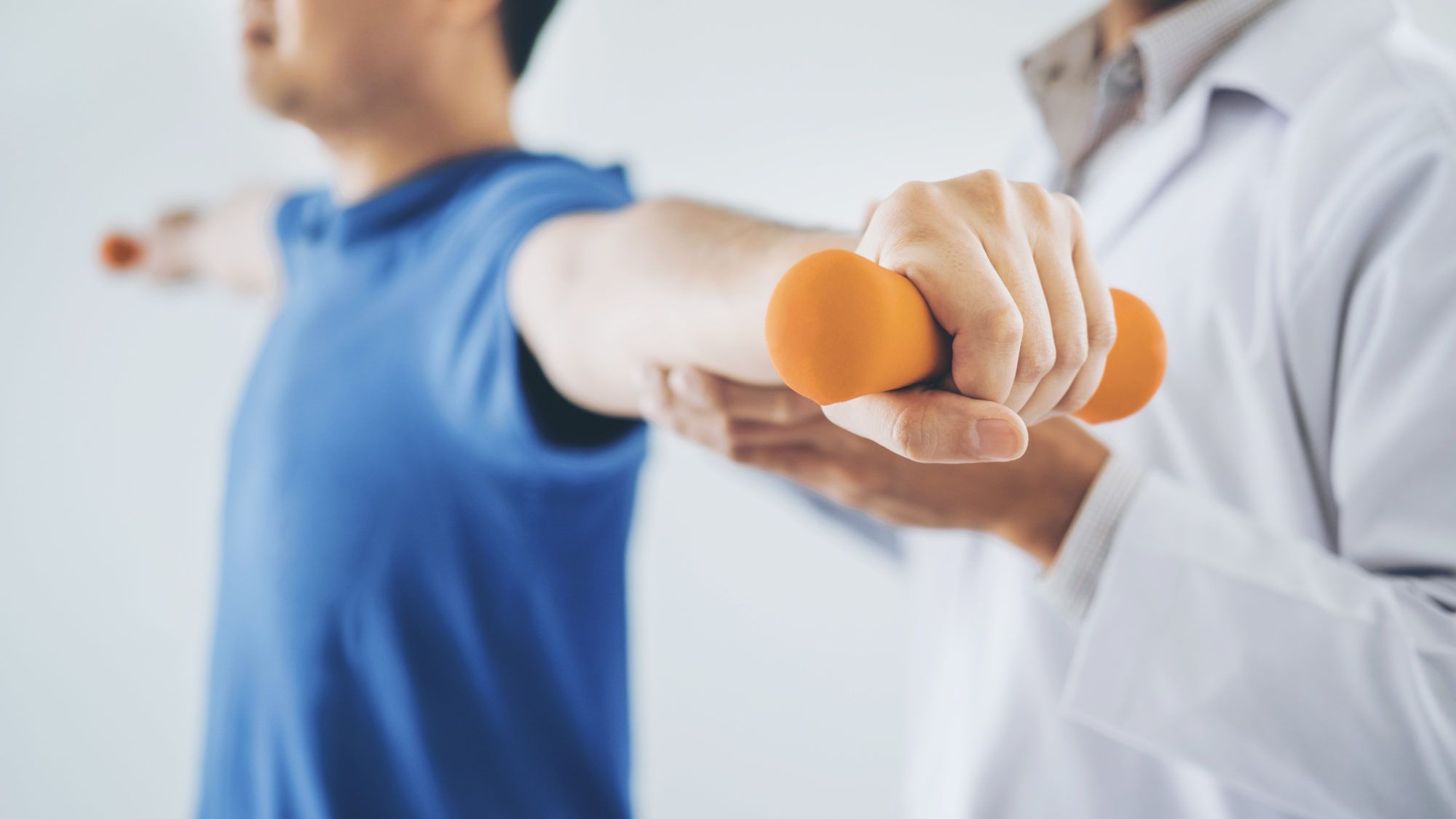 Physiotherapist helping patient exercise with dumbbells