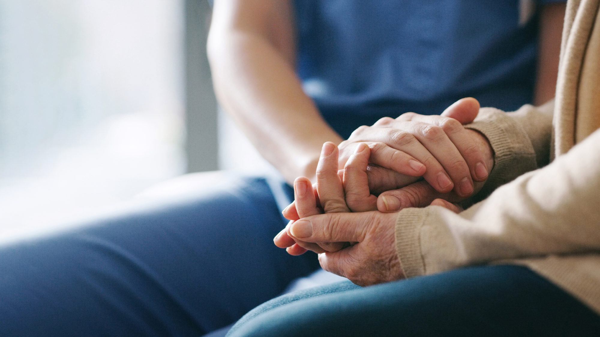 nurse holding senior patient's hand