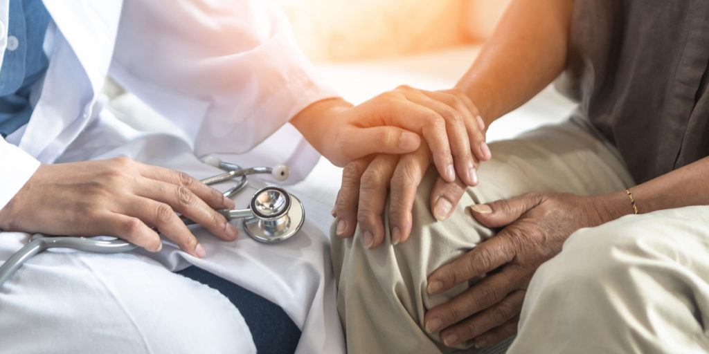 doctor holding senior patient's hand