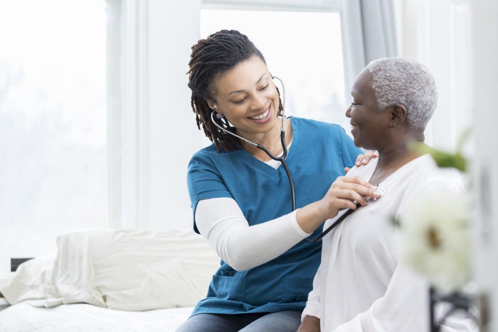 nurse using stethoscope on senior patient