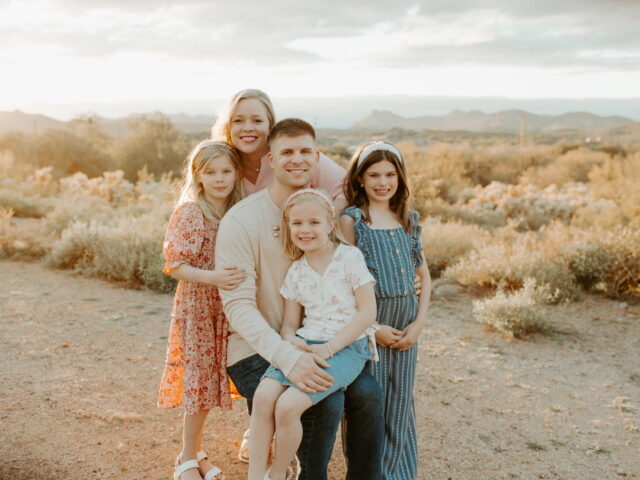 Joshua Zahn seated with his family in front of a sonoran desert landscape at sunset.