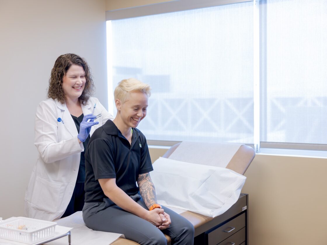 Dr. Lindsay Frerichs treating a migraine patient by administering botox injections in an exam room.