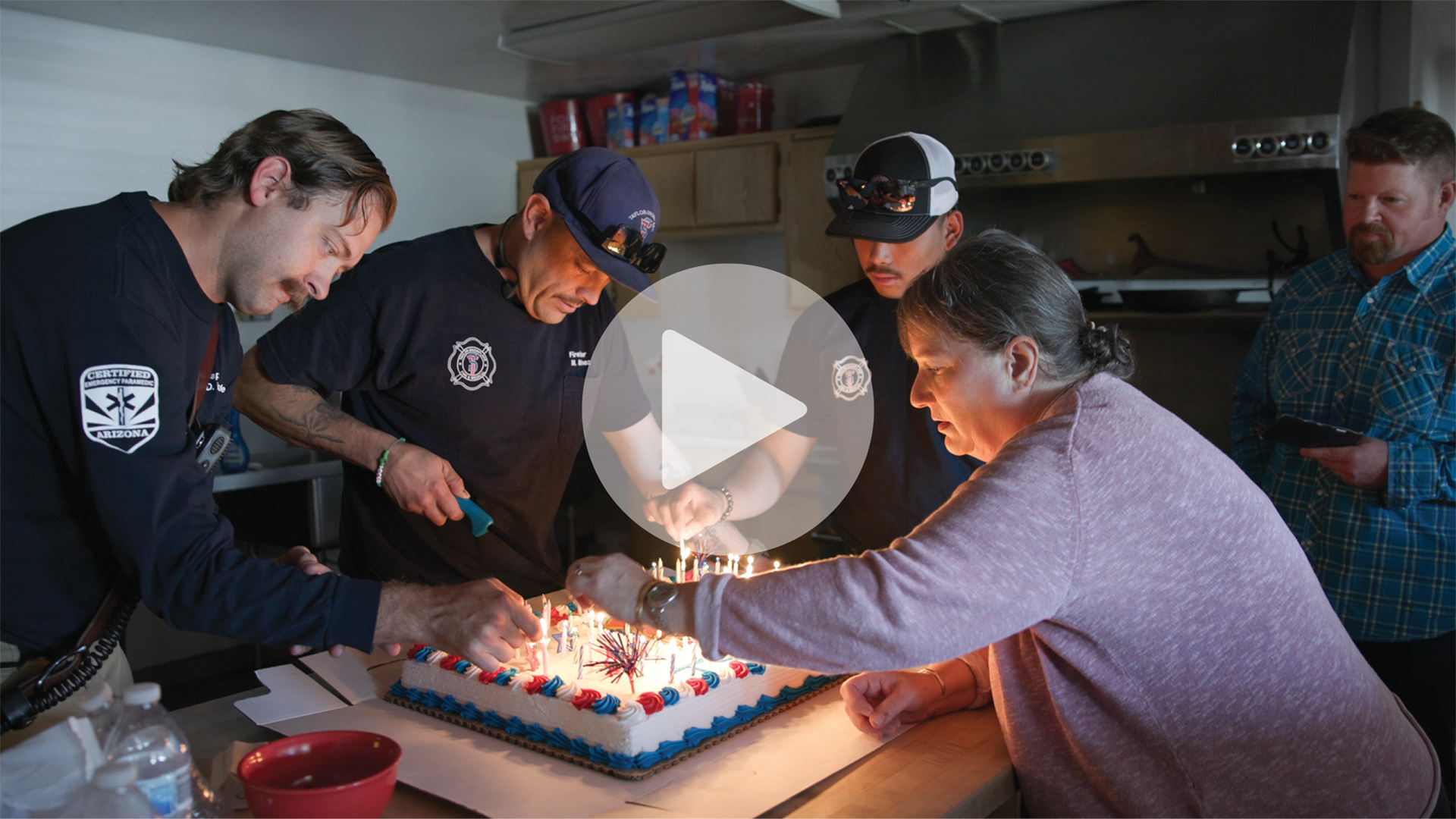 Lisa, her husband, and firefighters light the candles on a cake