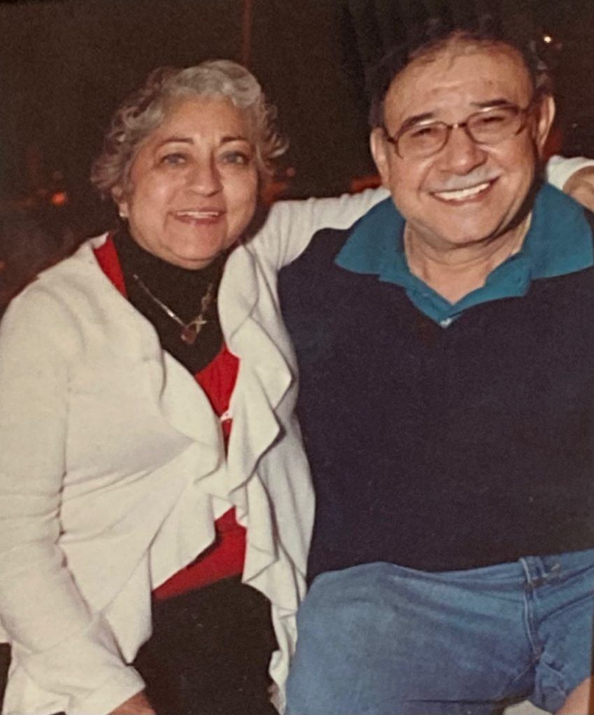 Maricela with her arm around her husband, Juan. The two are seated.