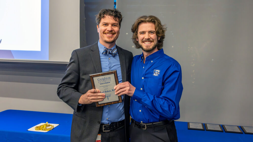 Dr. Michael Robers poses with his plaque at the CUSOM award ceremony.