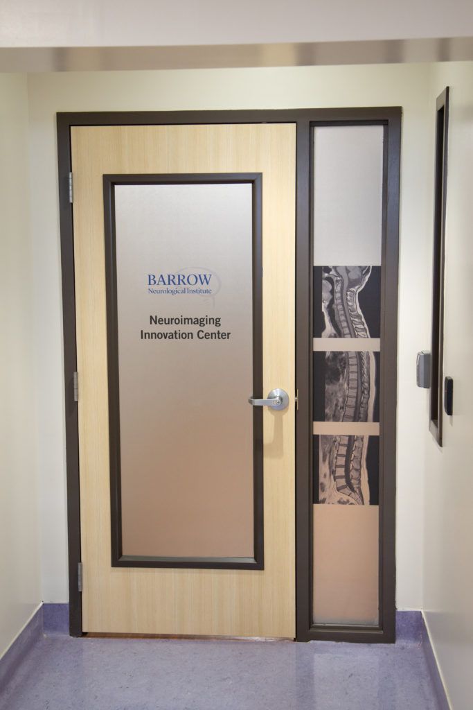 A door with frosted glass reads "Barrow Neuroimaging Innovation Center" and features a vertical image of the human spine.