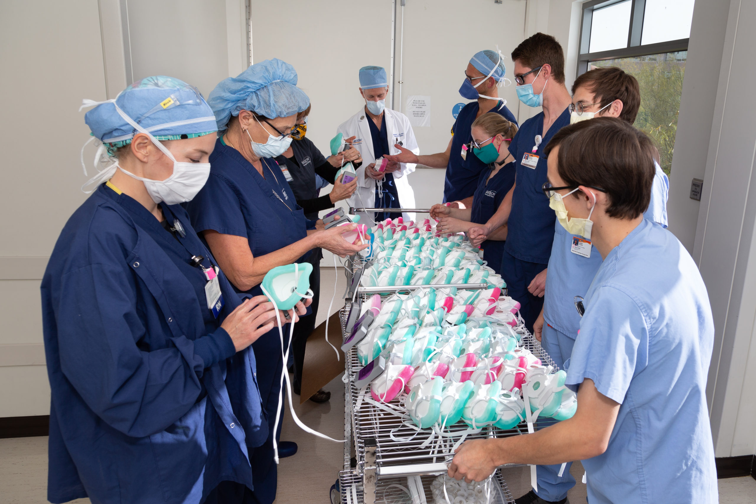 3D-printed p100 masks fill a table surrounded by health care workers