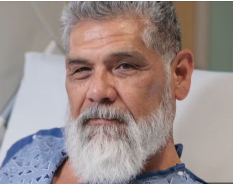 petznick stroke center patient richard flores smiling confidently in a hospital gown.