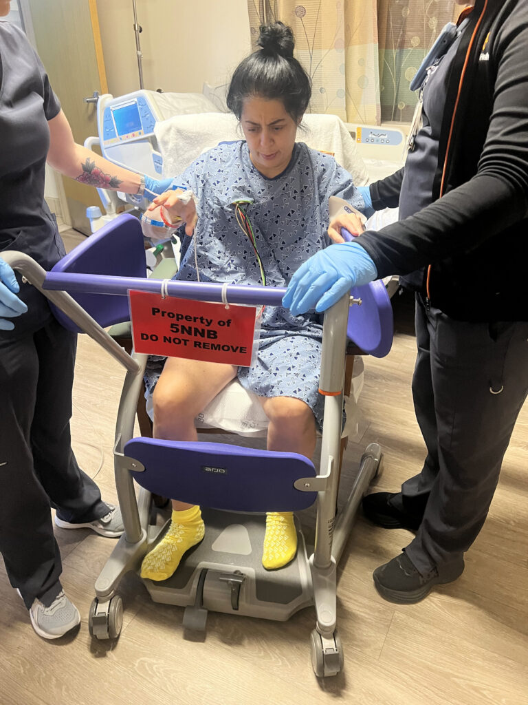 Barrow clinicians help Sabrina Mancini stand using a sit-to-stand aid
