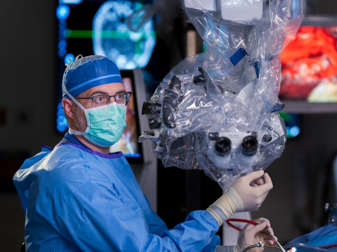 surgical neurotologist shawn stevens operating with a microscope and surgical instruments