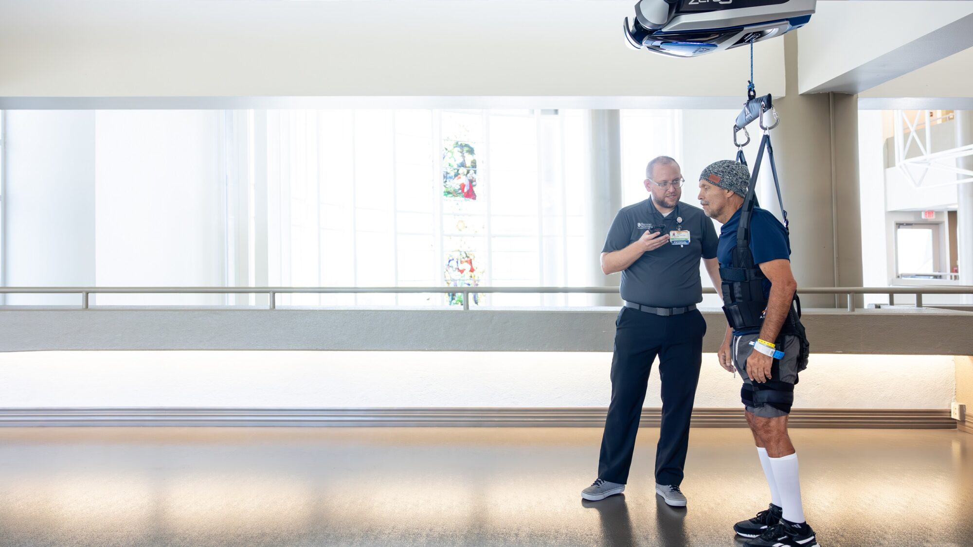 Barrow Neuro-Rehab patient walking with the help of his physical therapist and zero gravity technology.